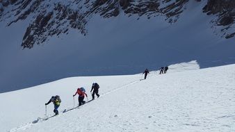 landscape of climbers descend from a snowy slope