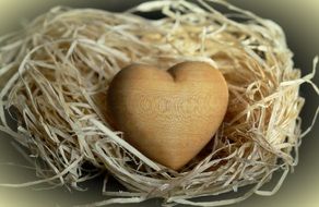 Beautiful, wooden heart lies on the yellow wool