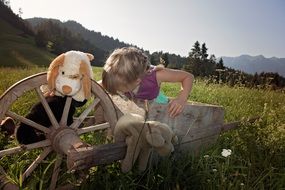 child with a soft toy in a green meadow