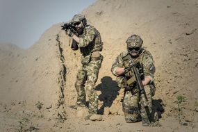 two soldiers in full gear in the desert