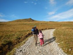 parent and child walk along a mountain path