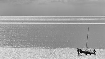 distant view of people near a boat on the ocean coast, uk, england, hunstanton