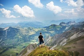 man on the peak of a mountain above a picturesque valley