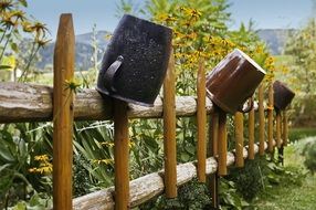 Beautiful wooden fence with pots near the colorful plants in the village