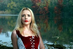 blonde with red lips on the background of the lake in autumn