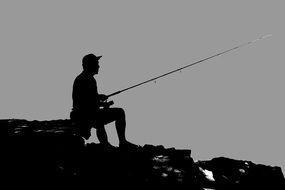 silhouette of a fisherman on a rock at dusk