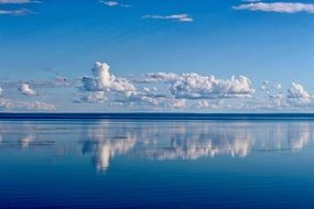 white clouds reflected in the blue water of the ocean