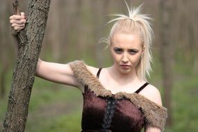 blonde girl in the forest in the costume of wild warrior