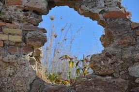 large hole in a stone wall among the ruins