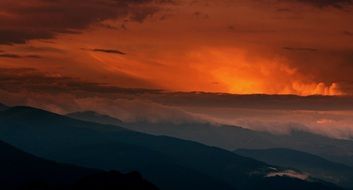 bright orange sunset in the clouds over the mountains