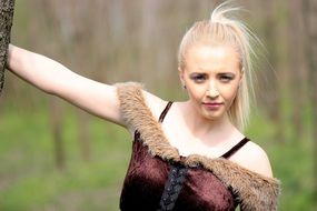 smiling girl in the forest in the costume of wild warrior