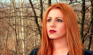 girl with long red hair on the background of the winter forest