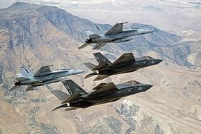 military aircraft in flight over the desert