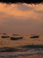 boats on the sea near the beach during sunset