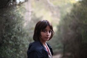 Portrait of girl in a black jacket on a background of the forest