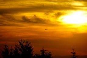 the plane is flying in the sky at sunset