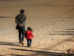 dad and daughter walk along the coast in cold weather
