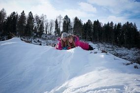 two happy Child Girls lay on Snow at forest