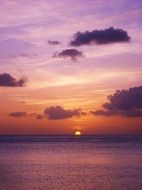 distant view of the orange and purple setting sun in the sea