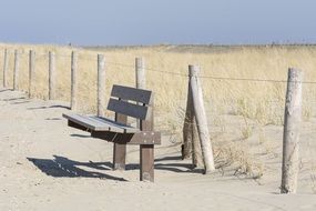 wooden bench on the beach near the fence