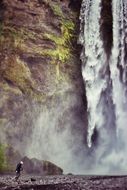 man stands near a cliff with a waterfall