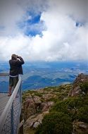 man looks through binoculars from an observation deck
