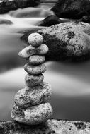 black white photo of the balance of stones on the shore of a pond