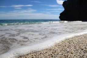 Landscape of sea foam and calm waves on the sandy shore