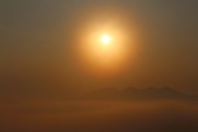 sun in cloudy haze over the mountains