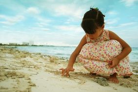 child playing with sand on the beach