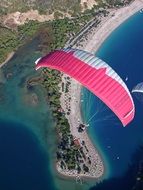 pink white parachute in the sky over the beach