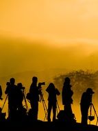 silhouette of photographers at beautiful and colorful sunrise near the lake among the plants