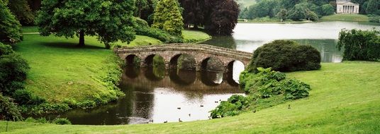 stone bridge over the river in a green park