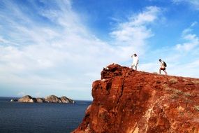 people on a rock watching the ocean