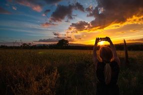 girl in the field photographs the sunset