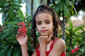 girl on a background of a plant with small red flowers