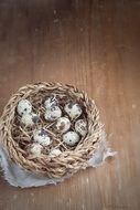 top view of quail eggs in a basket on a wooden surface