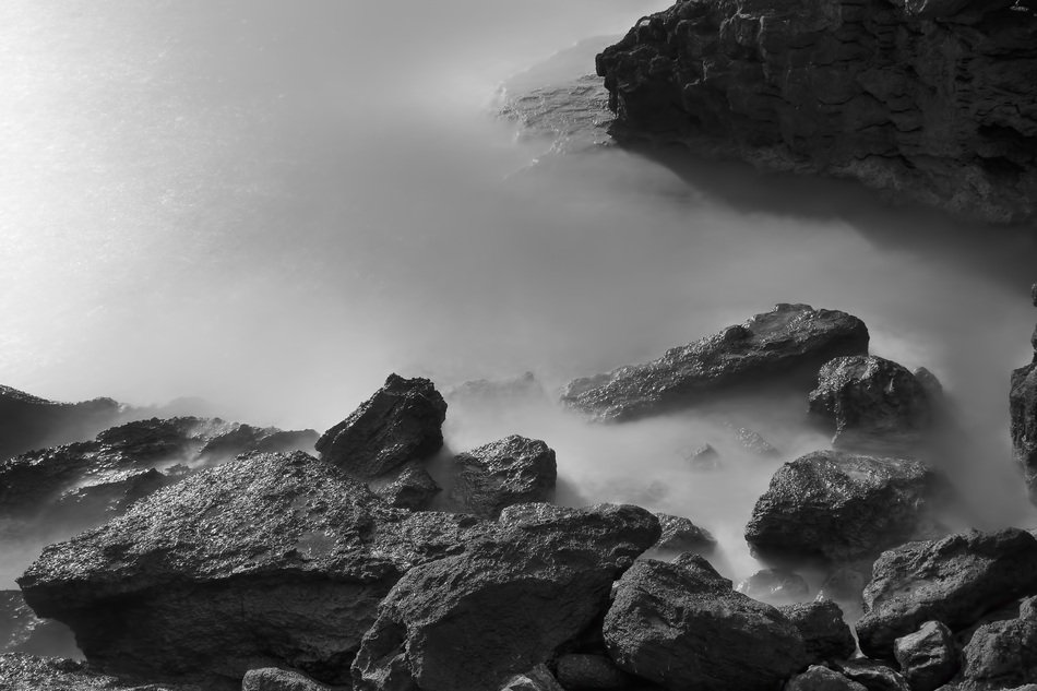 monochrome picture of fog over the rocks on the coast of Spain