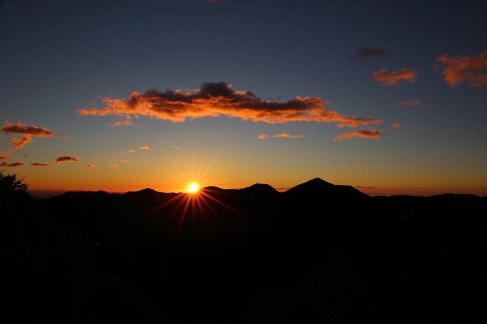 the bright sun peeks out from behind the ridge