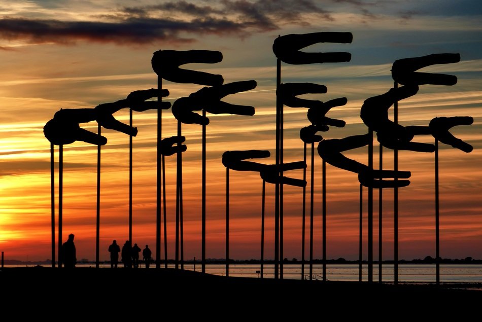 wind poles on the shore of the Wadden Sea at sunset