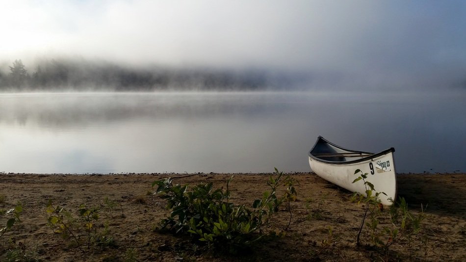 white Canoe on bank at foggy Lake