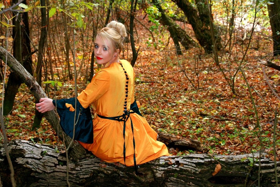 Girl in orange Dress on wooden log