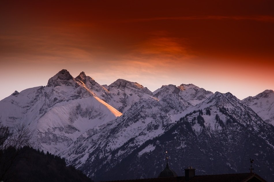 orange sky over the mountains in the snow at dusk