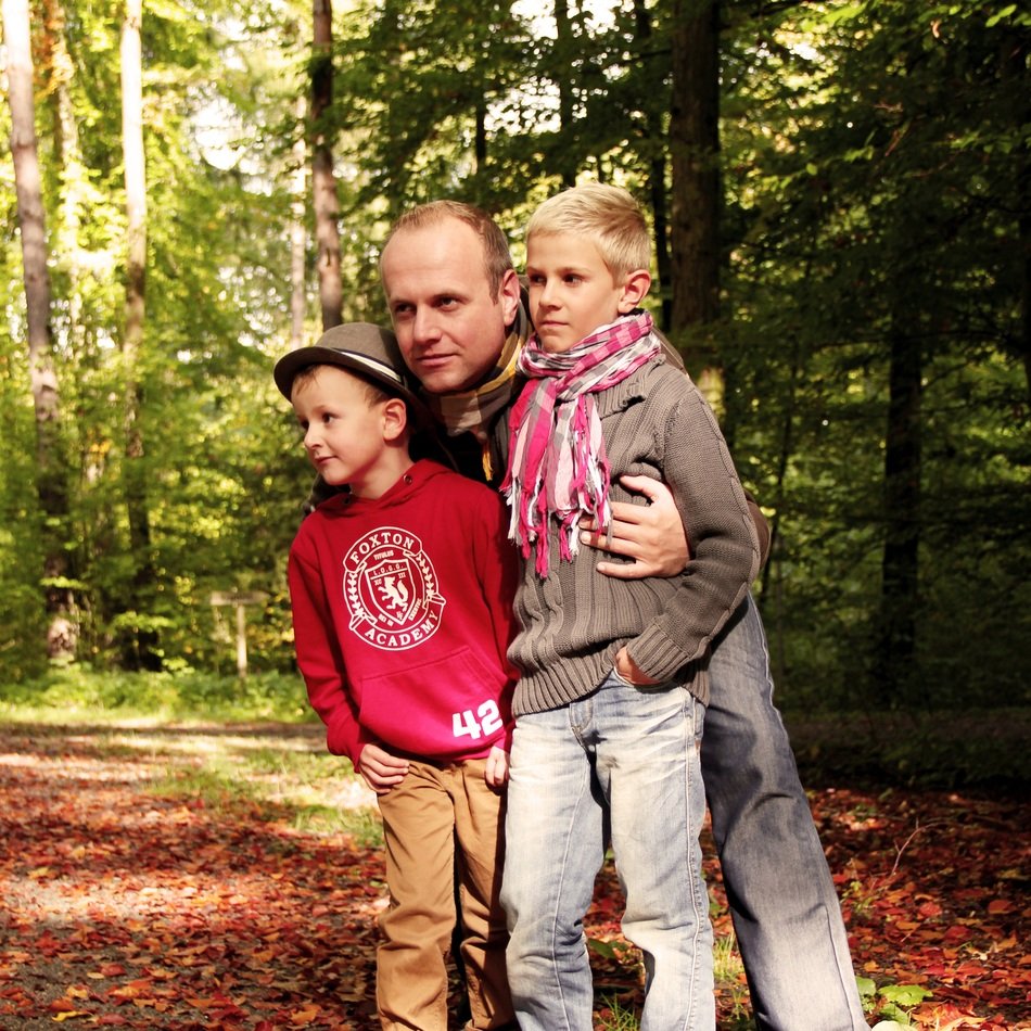 dad with sons stands in the forest