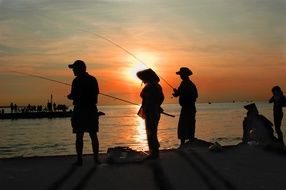 fishermen by the sea at sunset
