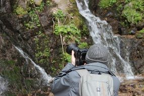 man photographs nature near a waterfall