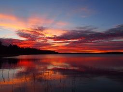 red sunset in the clouds over a lake in finland