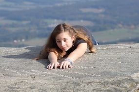 girl lies on the edge of a cliff