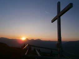 sunset over the cross on top of the mountain
