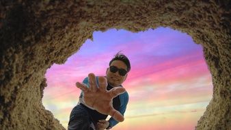 man with outstretched arm at the entrance to the cave